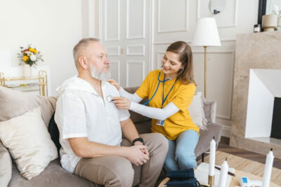 Carer using a stethoscope on a man's chest