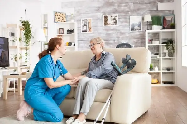 Care worker with an elderly lady sat on sofa