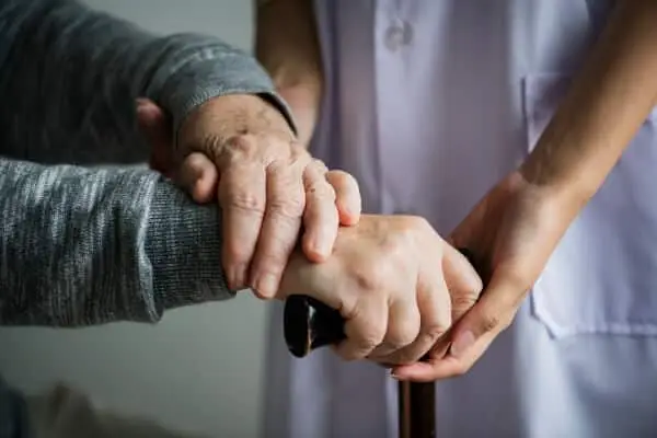 Nurse holding elderly person's hand