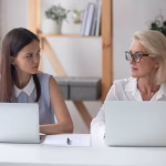 Different,Ages,Women,Colleagues,50s,And,Young,Female,Workmates,Sit