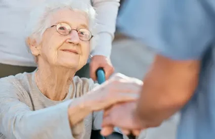 Holding hands, caregiver and senior woman in wheelchair for support outdoor in retirement home. Love, trust and healthcare nurse or medical wellness doctor for disability patient with kindness.