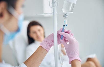 Experienced Caucasian heath care worker preparing a dark-haired female patient for the intravenous vitamin therapy