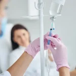 Experienced Caucasian heath care worker preparing a dark-haired female patient for the intravenous vitamin therapy