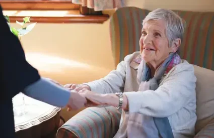 Nurse helping old woman holding hands in retirement home.