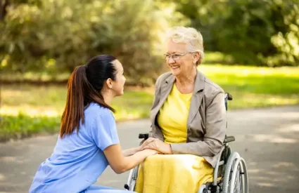 Nursing assistant taking care of elderly woman in wheelchair.