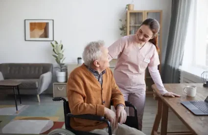 Portrait of smiling female nurse helping senior man in wheelchair at retirement home, copy space