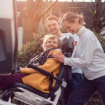 two care workers moving patient into vehicle
